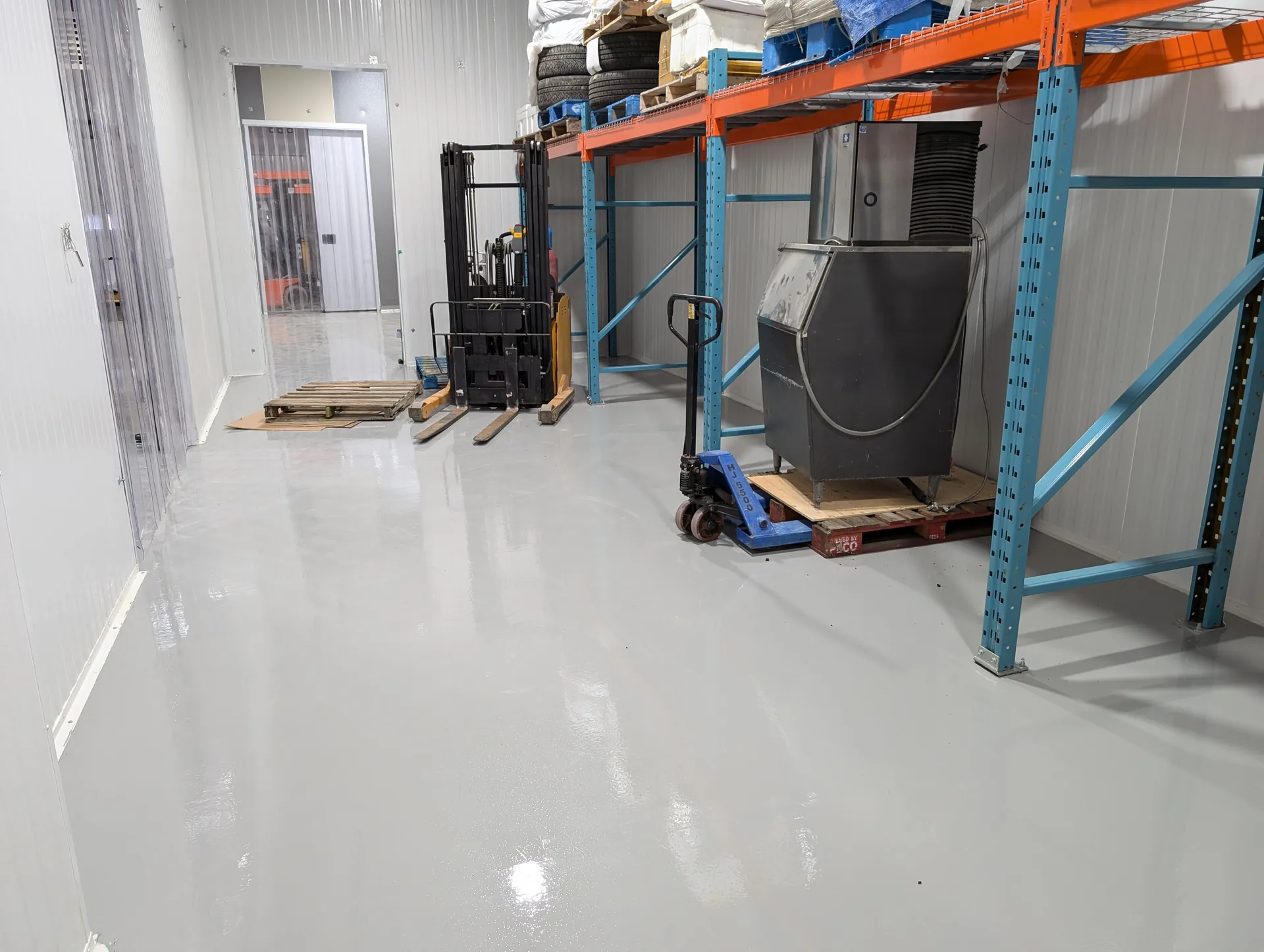 Epoxy & Polyaspartic Flooring in Mississauga, ON 3 Seamless grey warehouse floor beside storage racking in Mississauga