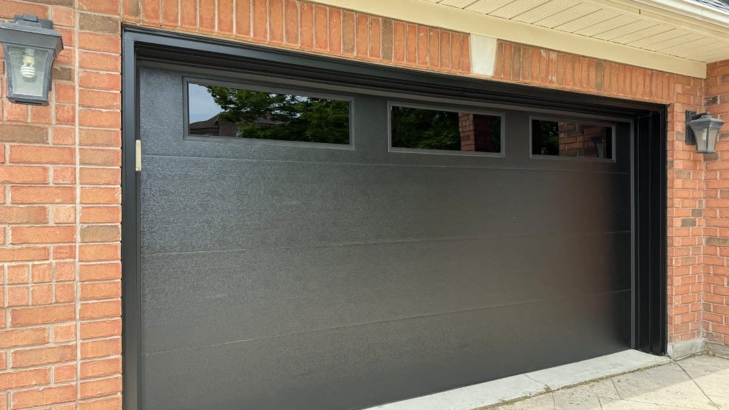 Charcoal garage door with three upper windows and brick surround